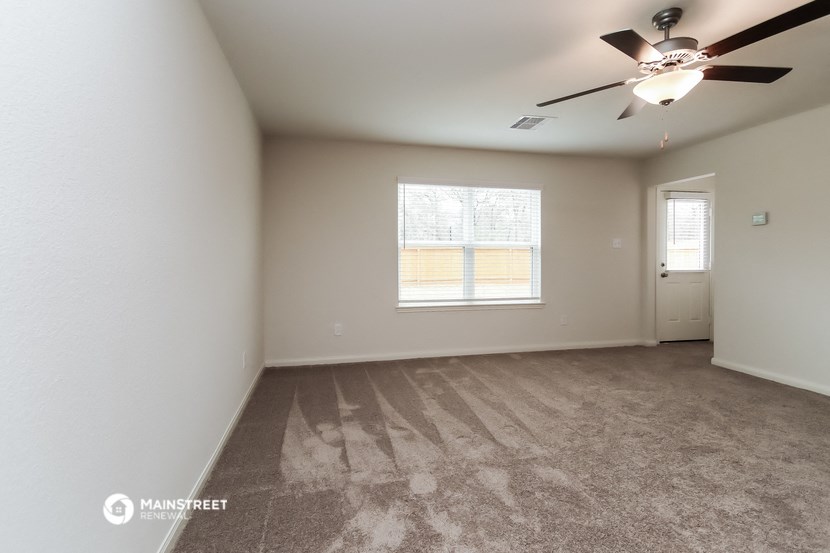 an empty living room with a ceiling fan and a window