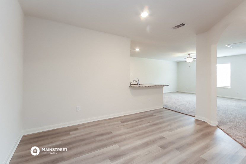 the living room and kitchen of a new home with white walls and wood flooring