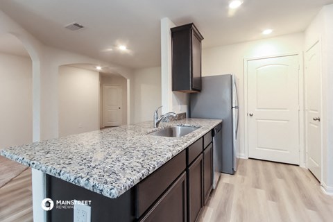 a kitchen with a granite counter top and a stainless steel refrigerator