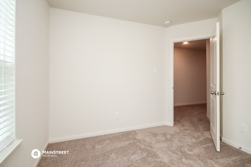 a bedroom with a door to a hallway and a carpeted floor