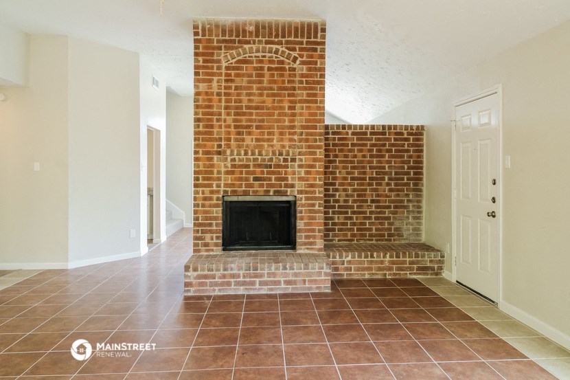 the living room has a brick fireplace and tile flooring