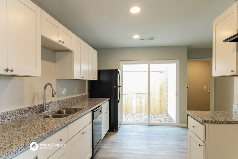 a kitchen with white cabinets and granite counter tops and a black refrigerator