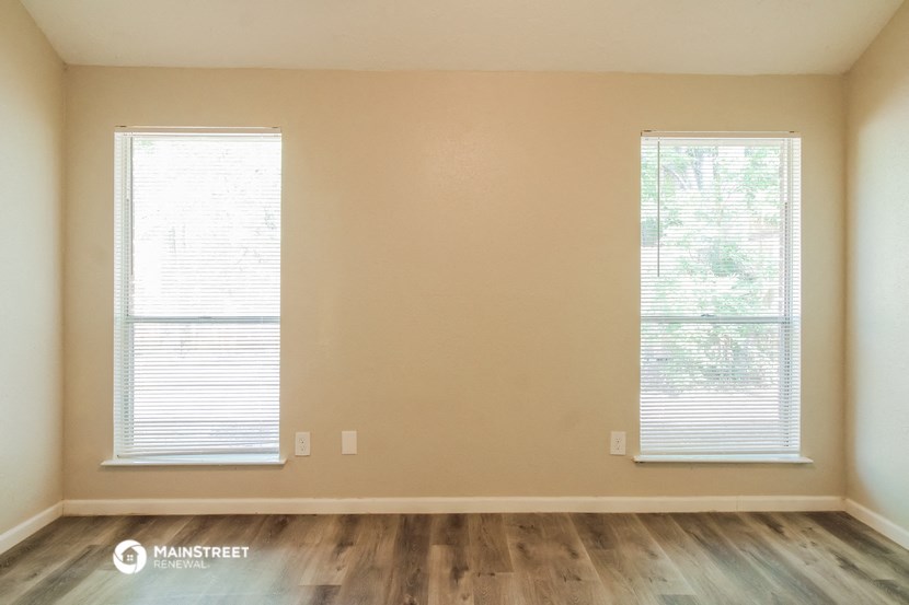 an empty living room with wood floors and two windows