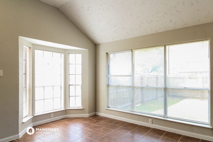 an empty living room with large windows and tiled floors