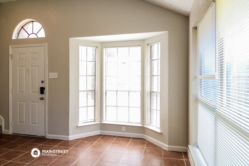 a living room with three large windows and a white door