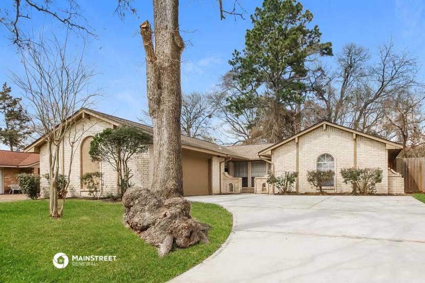 a tree that has fallen into a driveway in front of a house