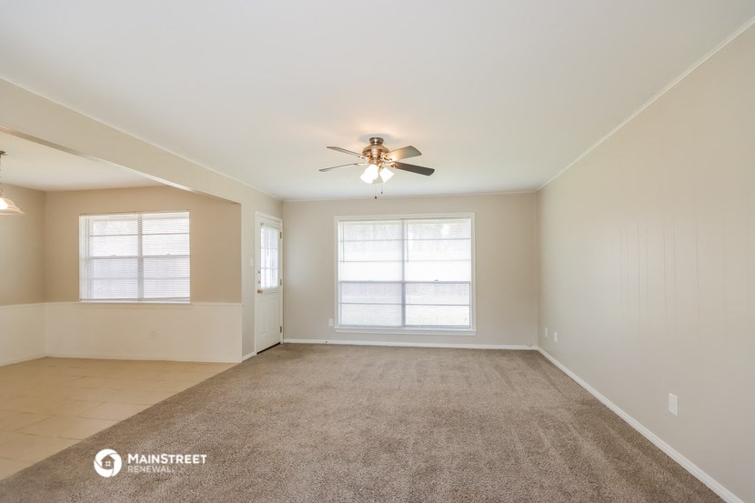 an empty living room with a ceiling fan and window