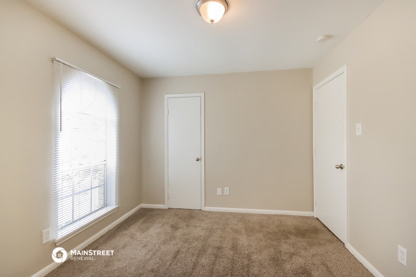 an empty living room with a large window and a door