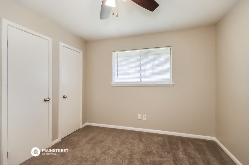 a bedroom with a closet and a window and a ceiling fan