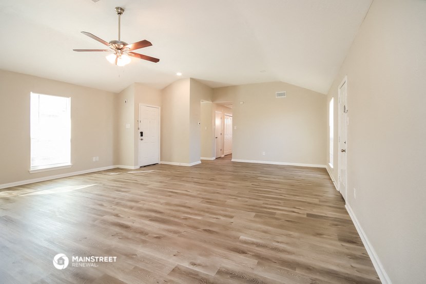 an empty living room with wood flooring and a ceiling fan
