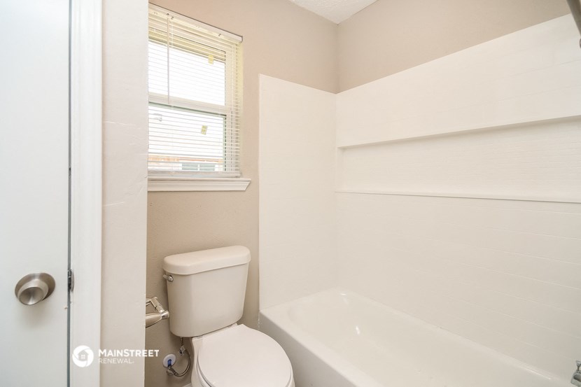 a bathroom with a toilet and a tub and a window