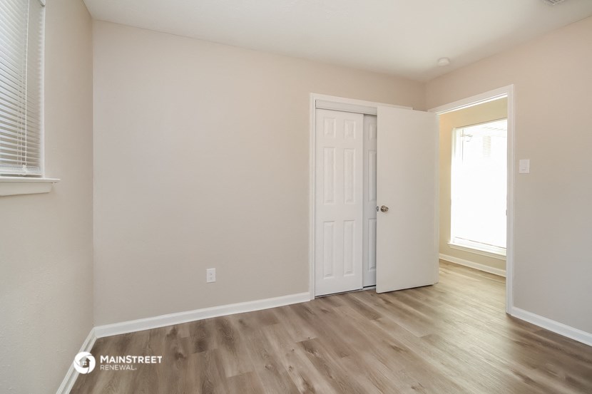 the spacious living room with wood flooring and a white door