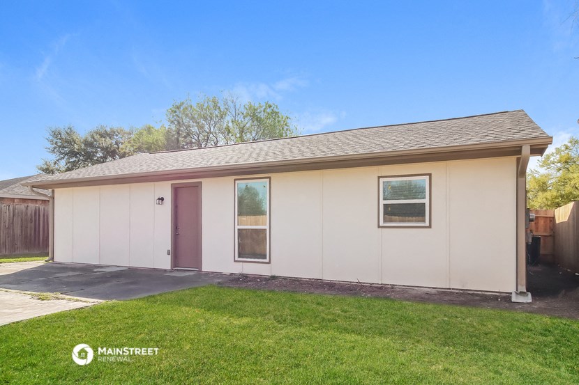 the front of a white house with a yard and a driveway