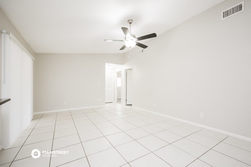 the living room and dining room of an empty house with a ceiling fan