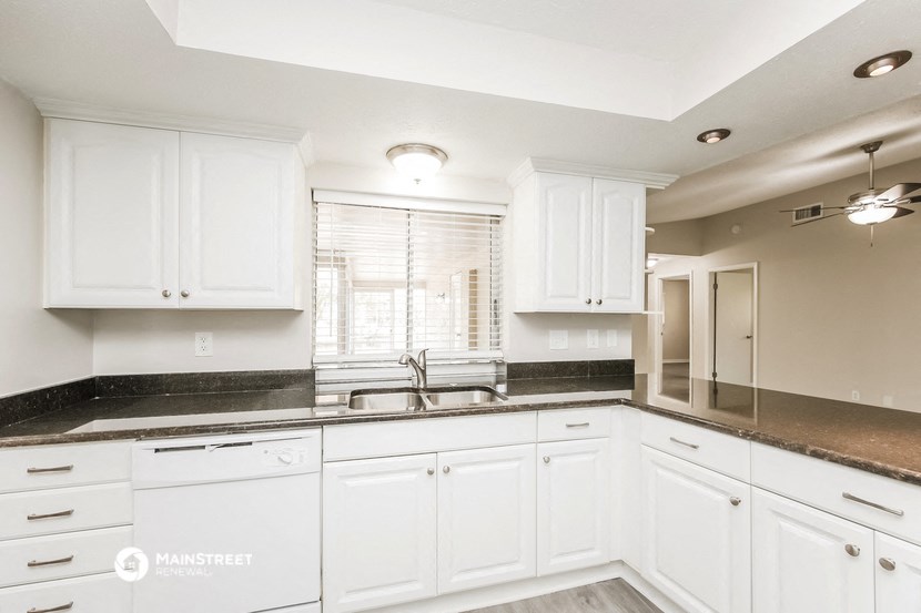 a white kitchen with white cabinets and black counter tops