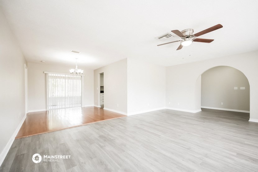 an empty living room with a ceiling fan and wood flooring