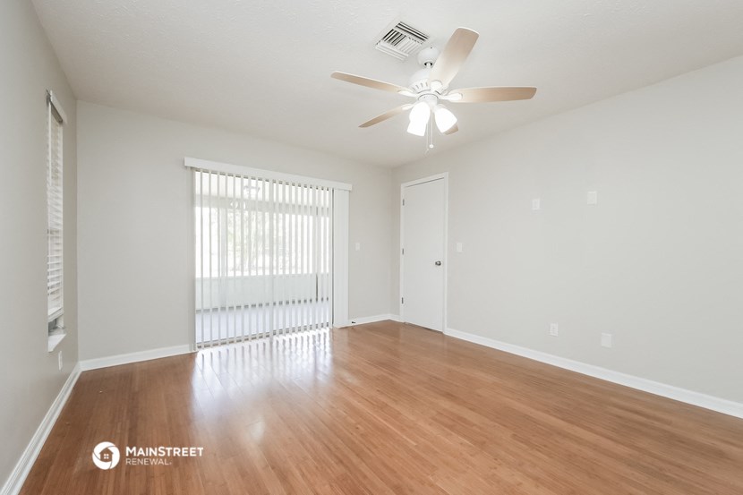 a spacious living room with wood flooring and a ceiling fan