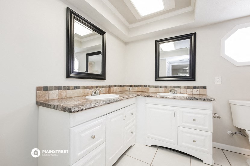 a white bathroom with two sinks and two mirrors