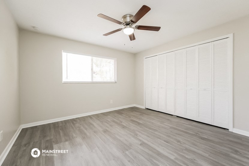 an empty living room with a ceiling fan and a large window