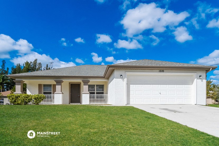 a white house with a garage and a green lawn