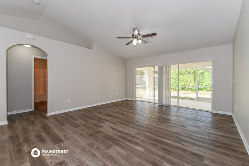 an empty living room with a ceiling fan and wood flooring