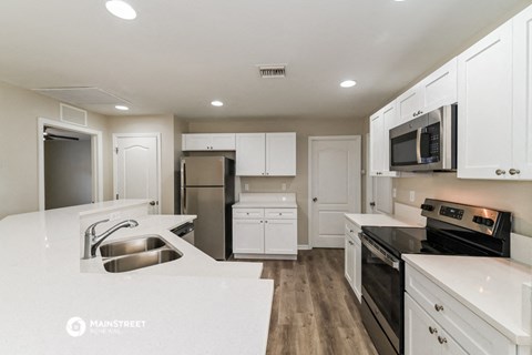 a white kitchen with black appliances and white counters