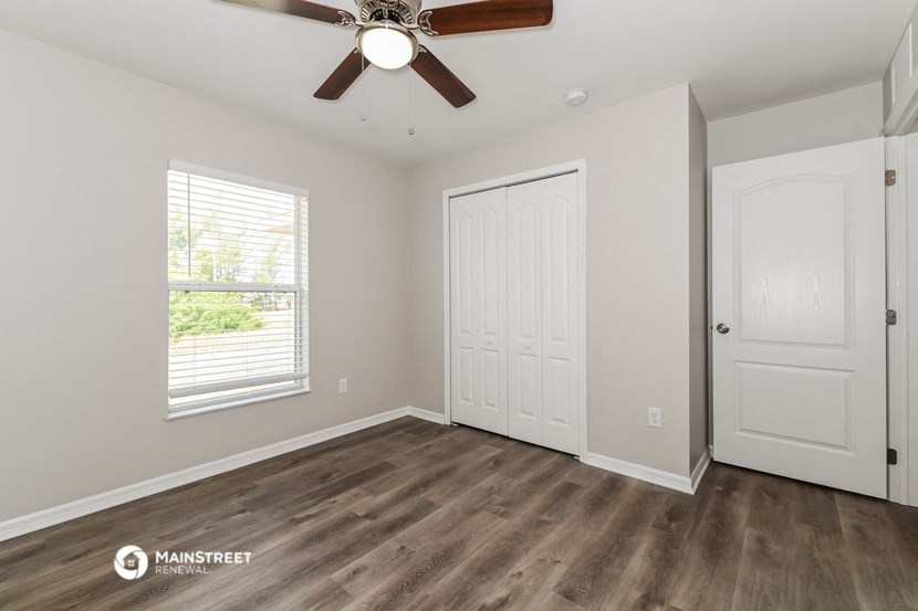 the living room of a home with a ceiling fan and a door