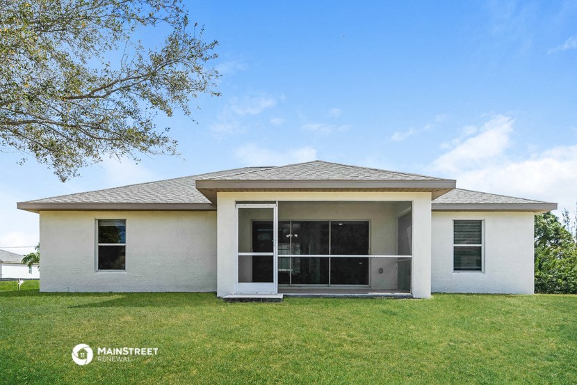 a small white house with a lawn and a tree