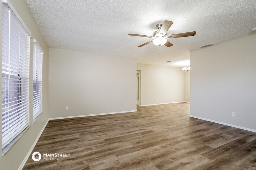an empty living room with a ceiling fan and a window
