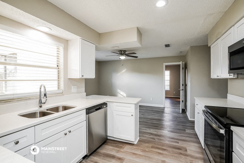 an empty kitchen with white cabinets and stainless steel appliances