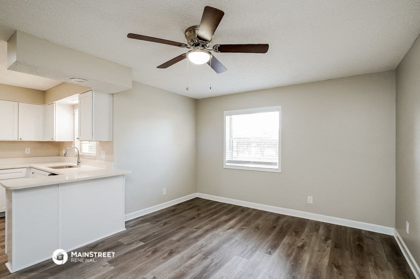 an empty living room and kitchen with a ceiling fan
