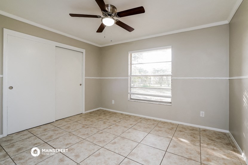 an empty living room with a ceiling fan and a window