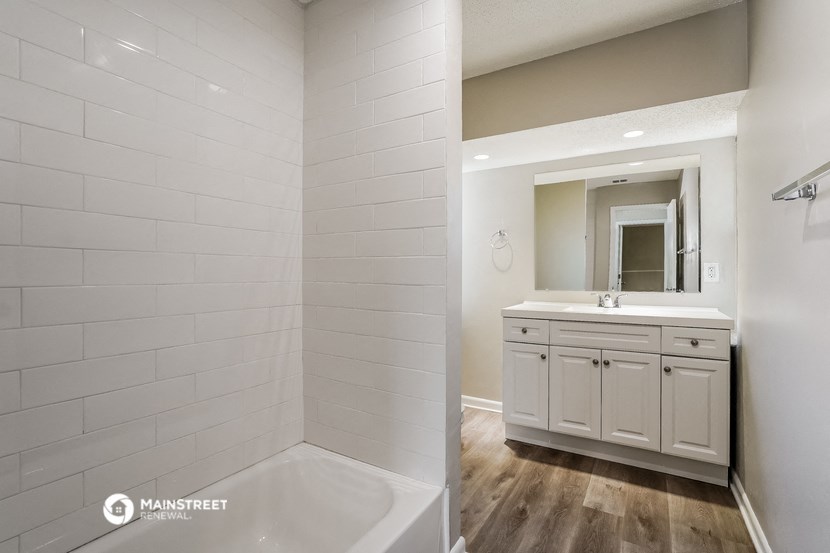 a bathroom with a tub and a sink and a mirror