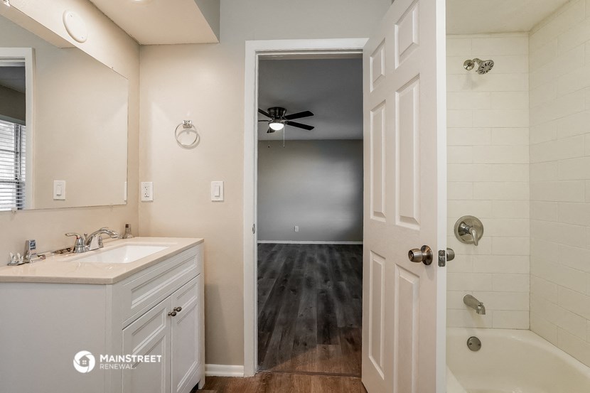 a bathroom with a sink and a bath tub and a door to a hallway