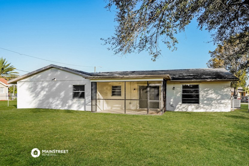 a small white house with a yard and a tree