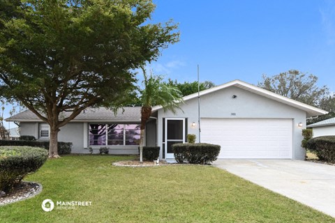a white house with a lawn and a tree