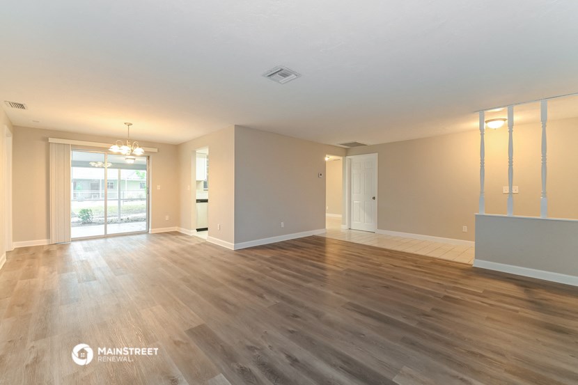 the living room and dining room of an empty house with wood flooring
