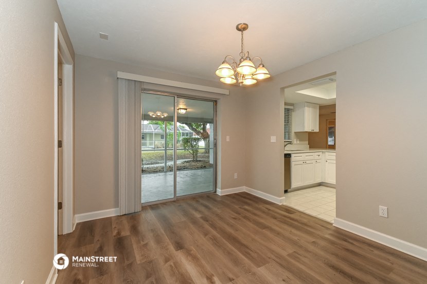 a living room with a door to a kitchen and a chandelier