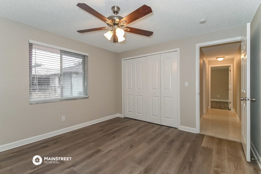 the spacious living room has a ceiling fan and a door to the hallway