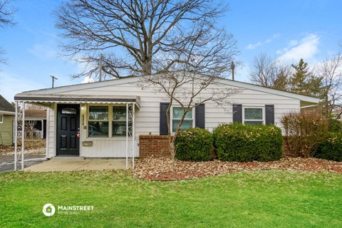 a small white house with a black door and a lawn