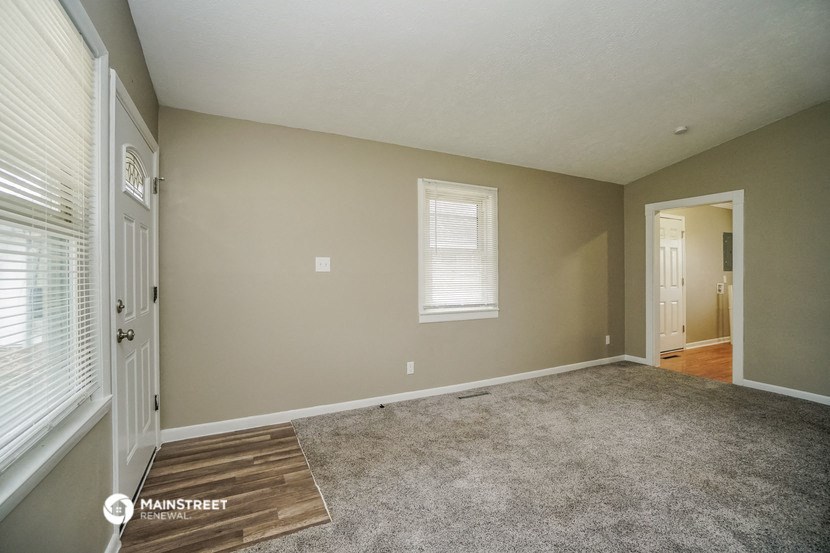 the living room of a house with carpet and a door