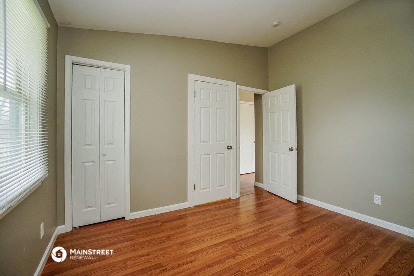 a bedroom with two closets and a wood floor and two doors