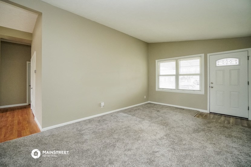an empty living room with a white door and a window