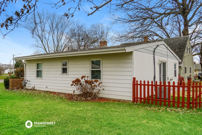 a small white house with a red fence
