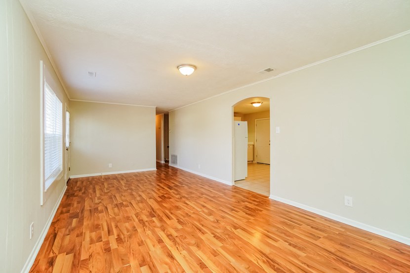 an empty living room with hard wood flooring and a large window