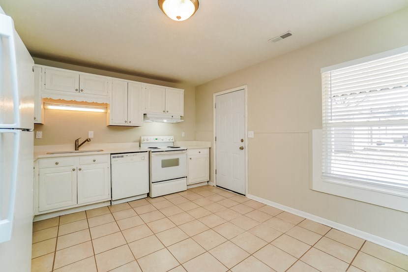 an empty kitchen with white appliances and white cabinets