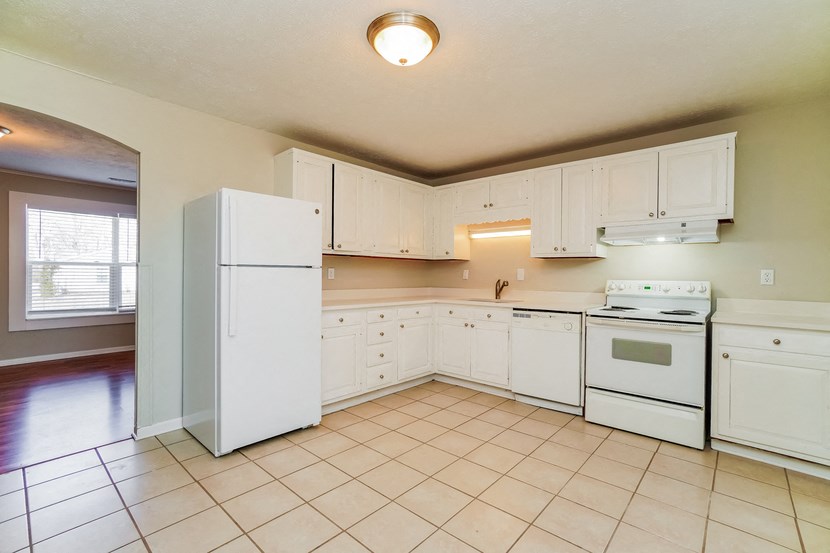 an empty kitchen with white appliances and white cabinets