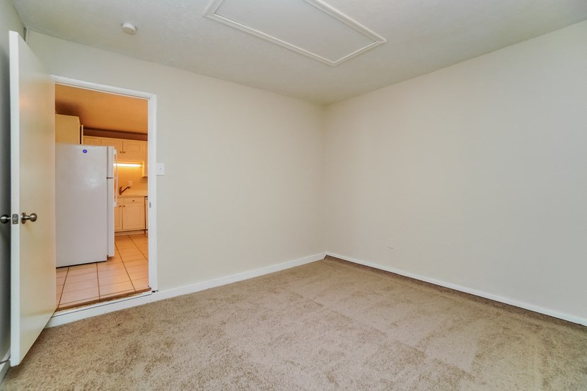 an empty living room with a door to a kitchen