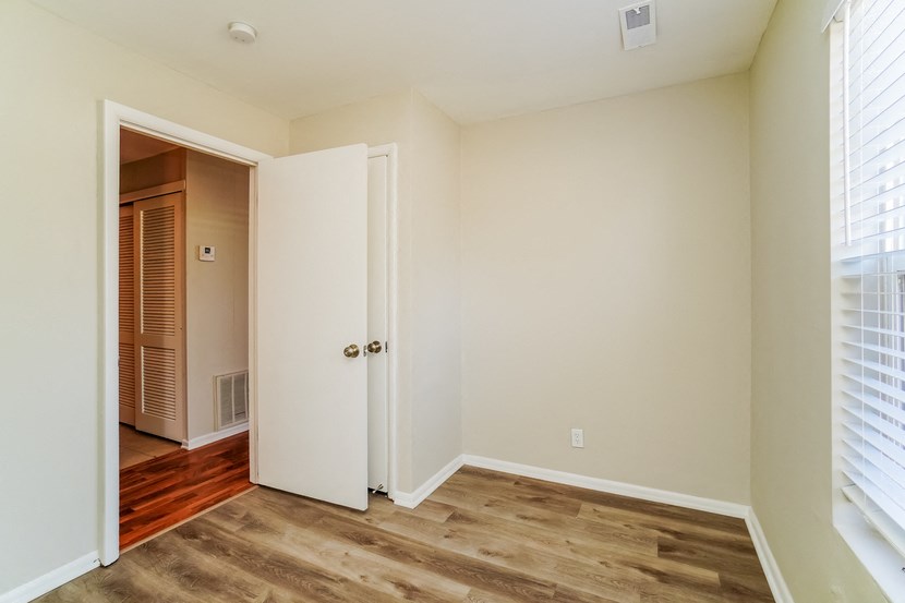 an empty bedroom with wood floors and a door to a closet