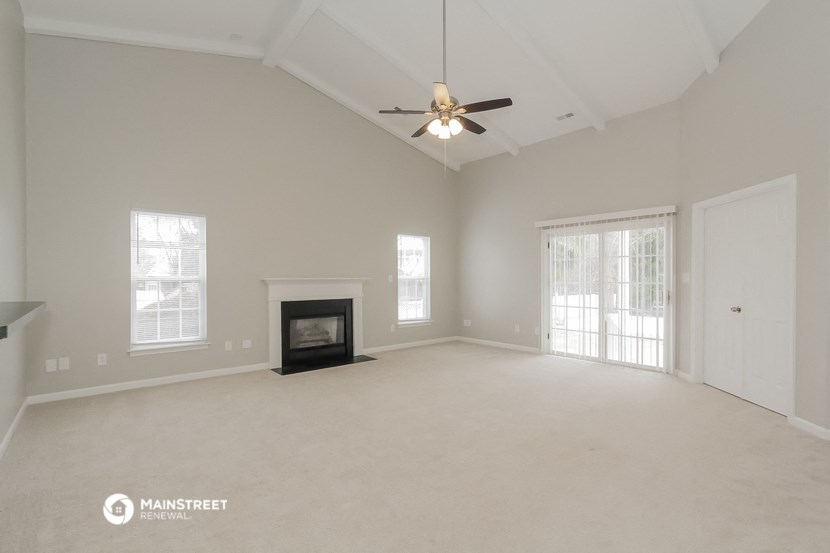 the spacious living room with fireplace and ceiling fan